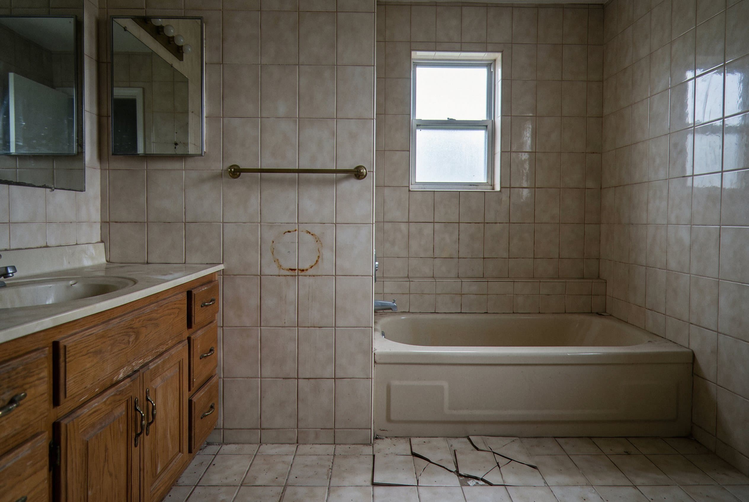 Dated tan tile bathroom with a cracked floor