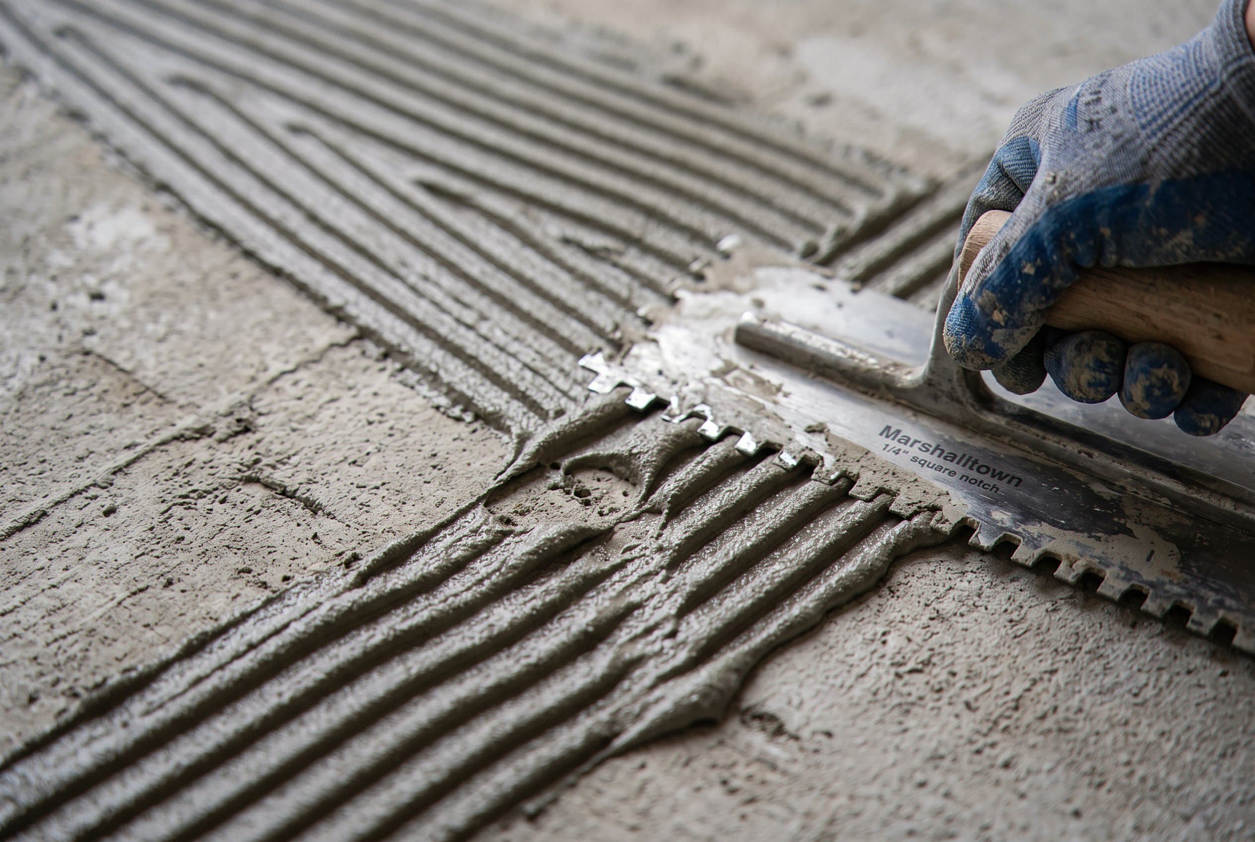 Trowel combing ridges into fresh floor thinset