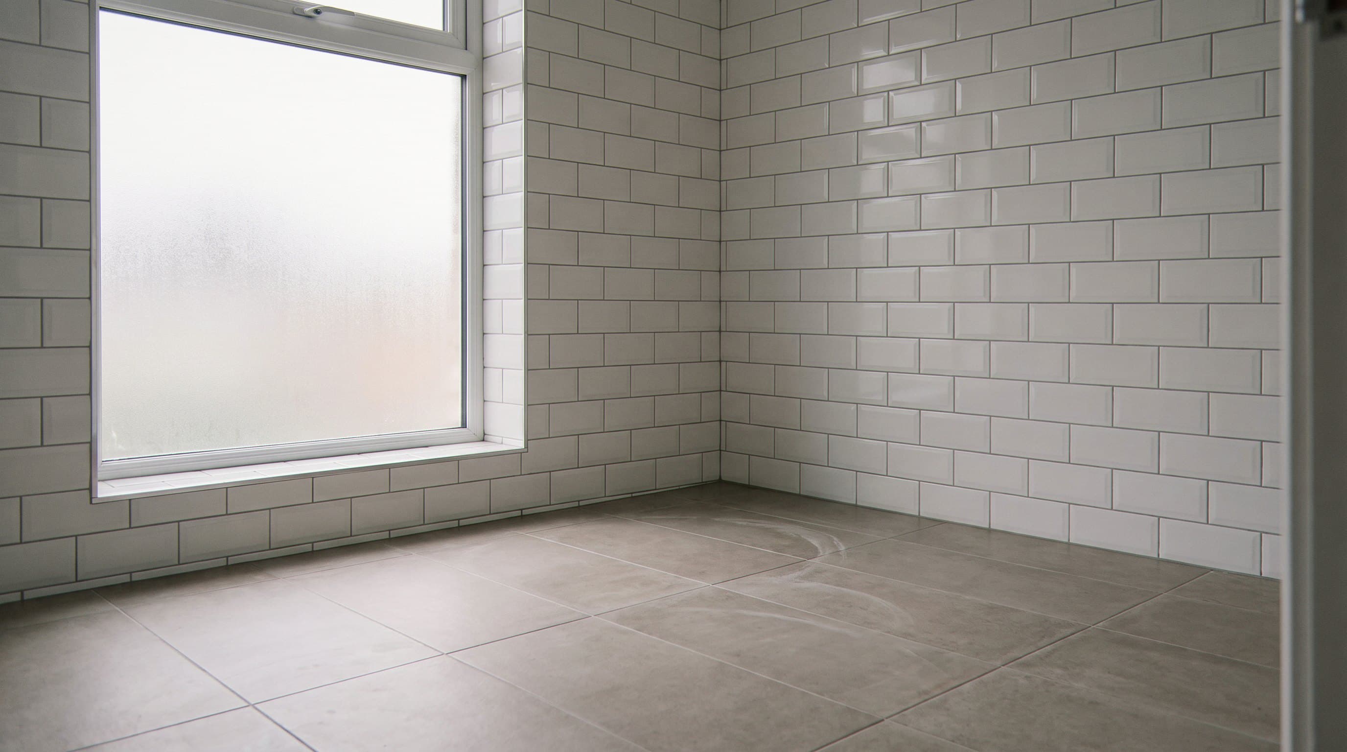 Empty subway-tiled room with frosted window and tile floor