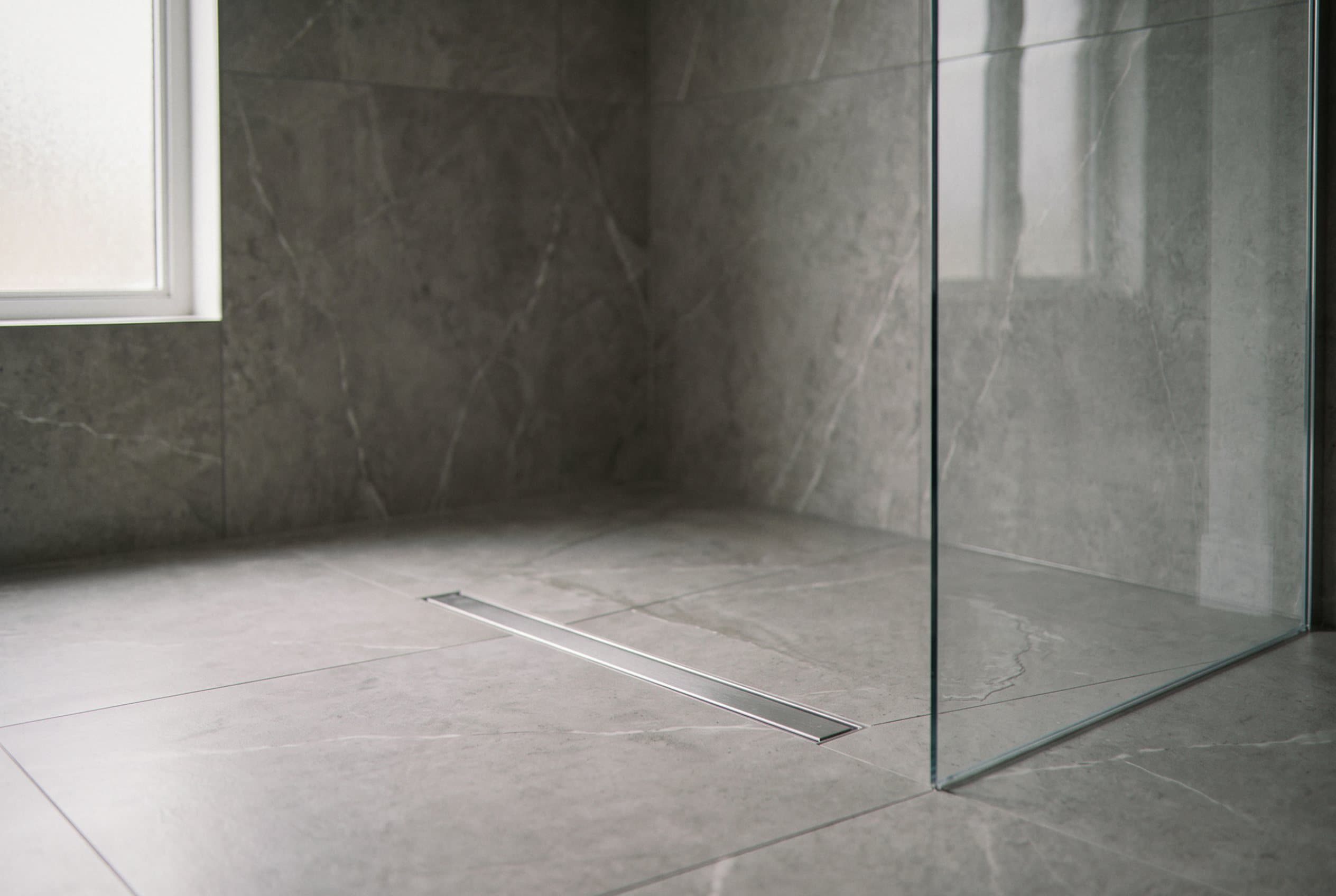 Curbless shower with grey tile and linear drain
