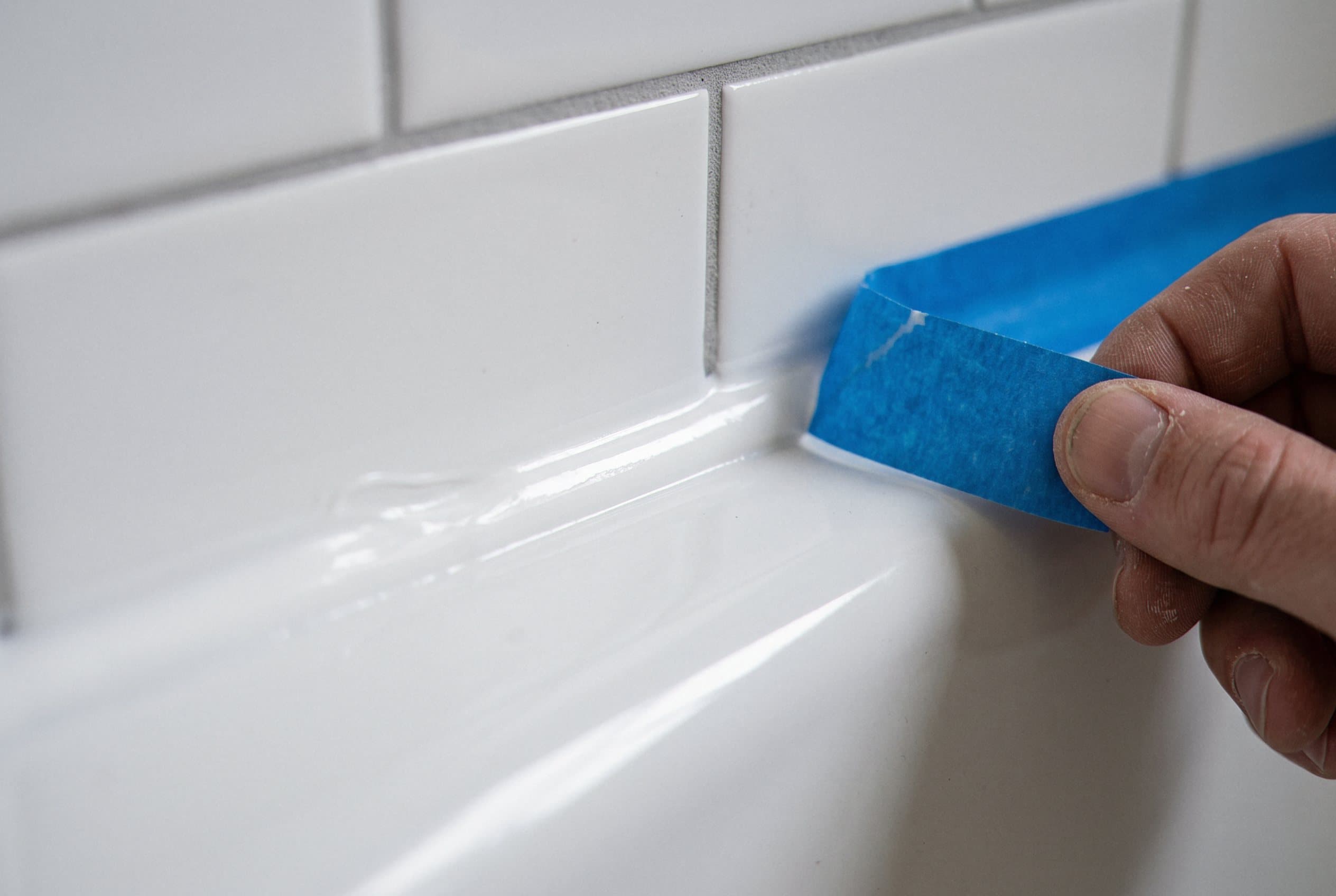 Taping a fresh caulk line on white tile