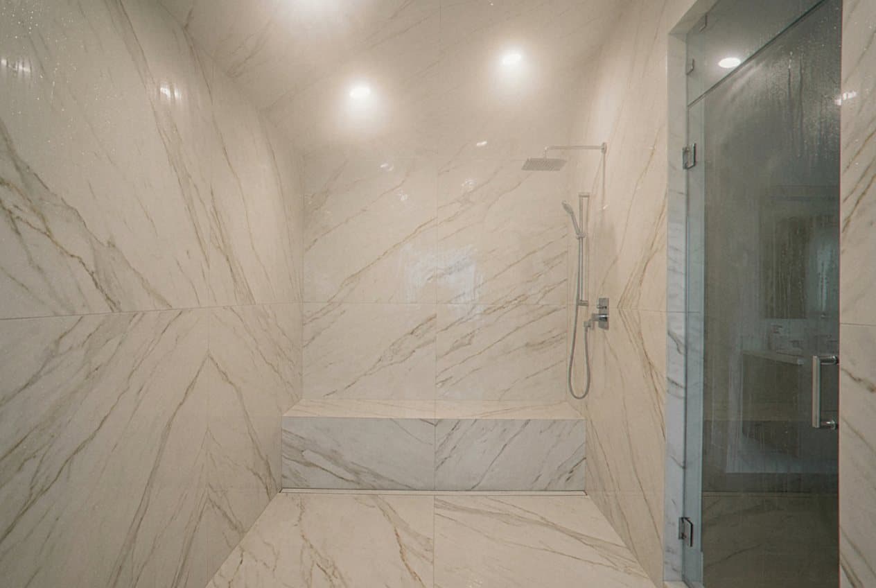 Marble-look steam shower with rain shower head overhead