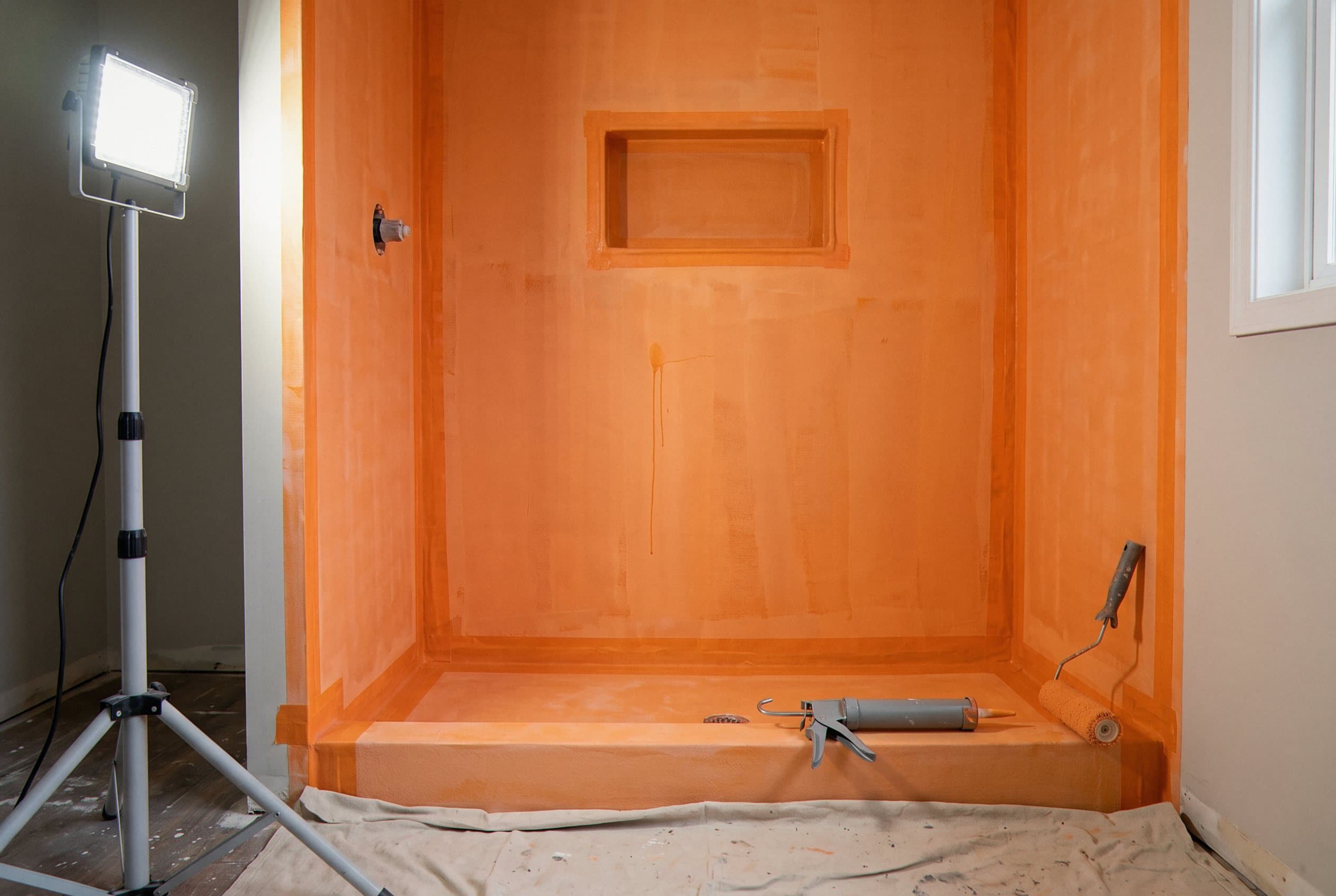 Orange waterproof membrane coating a shower niche and pan
